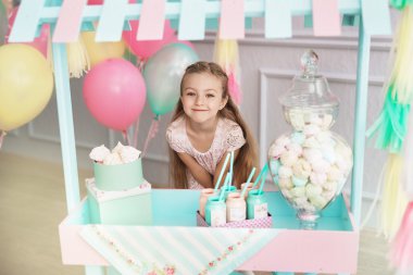 Güzel küçük bir kız oyuncak şeker dükkanın duruyor