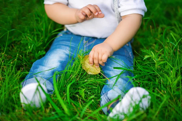 Ένα πόδια ενός ανθρώπου μωρού στο τζιν σε ένα πράσινο γρασίδι — Φωτογραφία Αρχείου