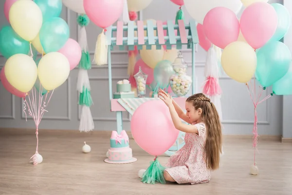 Little girl sits in a studio decorated colorful baloons — Stock Photo, Image