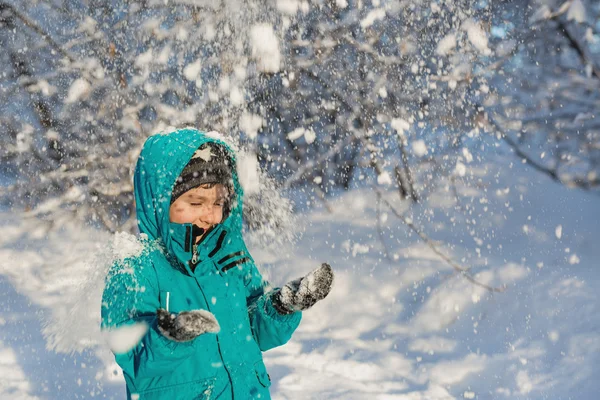 Un bambino carino sta sotto la neve che cade — Foto Stock
