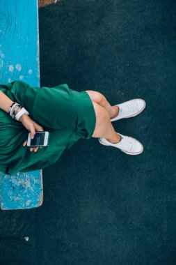 Kız bir bankta onu smartphone ile oturuyor.