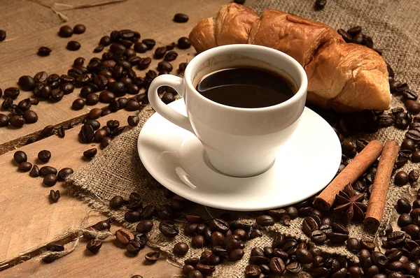 Kahve fincanı kahve çekirdekleri kruvasan, torbalama üzerine tarçın ile ve