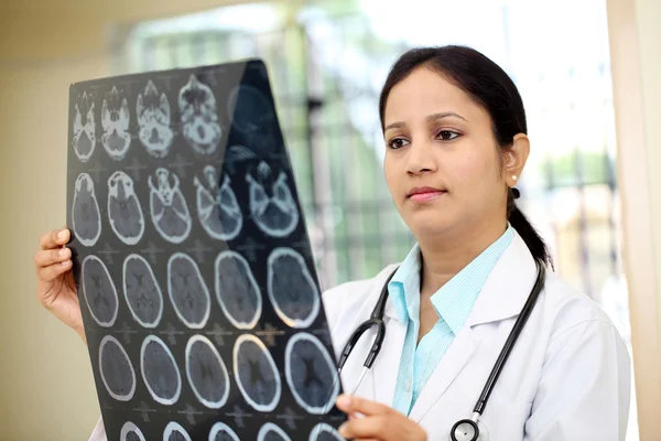 Kadın doktor beyin bilgisayarlı tomografi inceleyerek inceden inceye gözden geçirmek