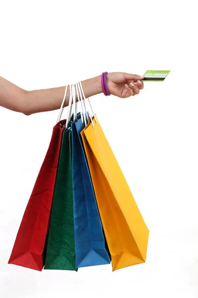 Mano femenina sosteniendo bolsas de compras y tarjeta de crédito en respaldo blanco —  Fotos de Stock