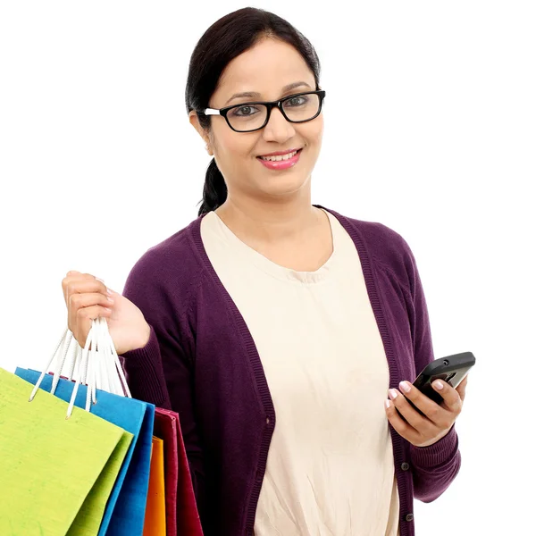 Joven mujer alegre sosteniendo bolsas de compras y teléfono móvil —  Fotos de Stock