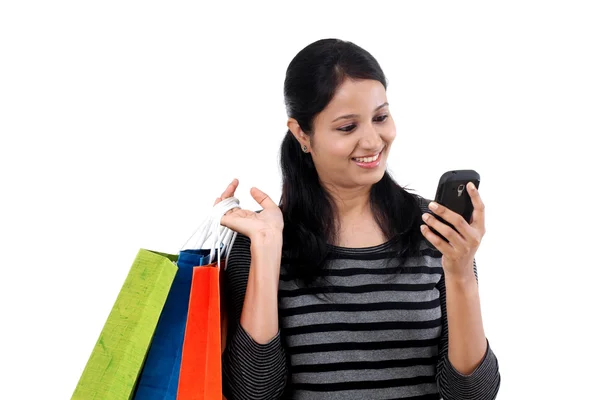 Young woman looking mobile phone and holding shopping bags Royalty Free Stock Photos