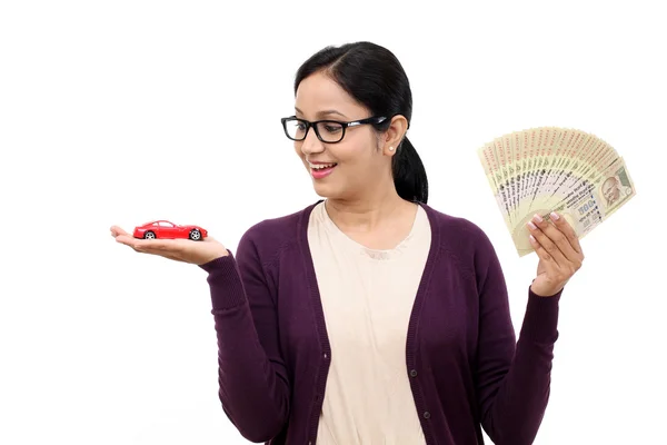 Jovem segurando um carro de brinquedo e notas de rupia indiana — Fotografia de Stock