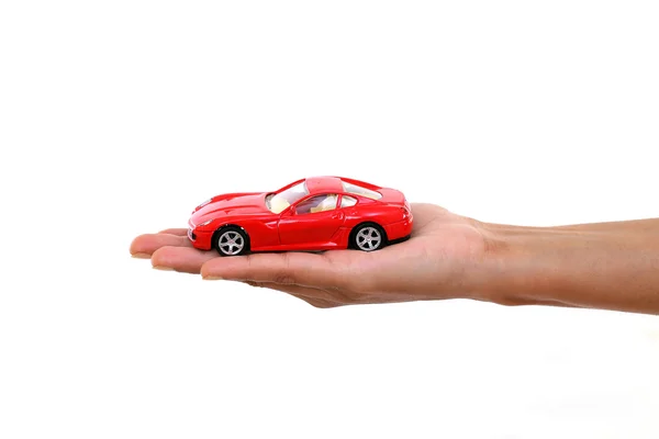 Mão segurando carro de brinquedo vermelho contra branco — Fotografia de Stock