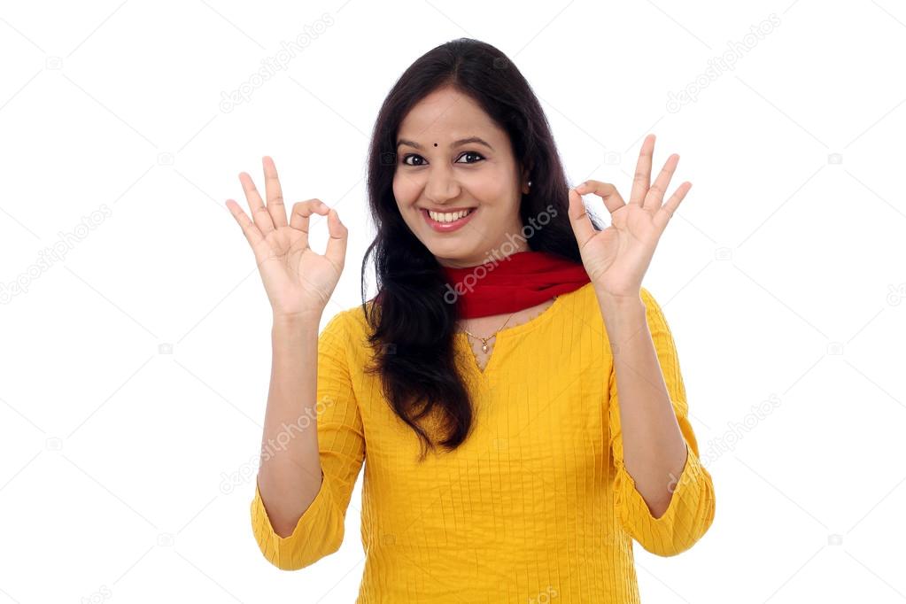 Young woman showing OK sign against white background