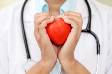 Kadın doktor güzel kırmızı kalp şekli tutan 