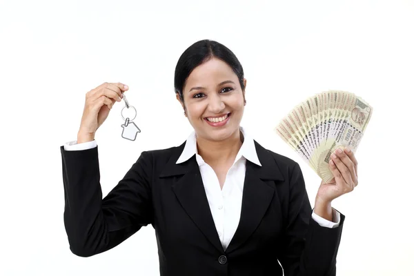 Businesswoman holding house key and currency notes — Stock Photo, Image