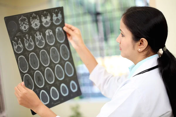 Kadın doktor beyin bilgisayarlı tomografi inceleyerek inceden inceye gözden geçirmek