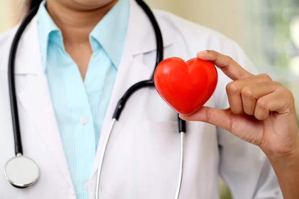 Female doctor holding a beautiful red heart shape — Stock Photo, Image
