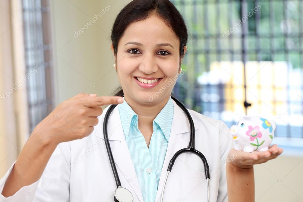 Young female doctor holding piggy bank