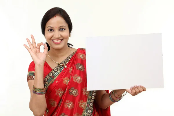 Traditionele vrouw houdt van een leeg reclamebord en het maken van ok gestur — Stockfoto