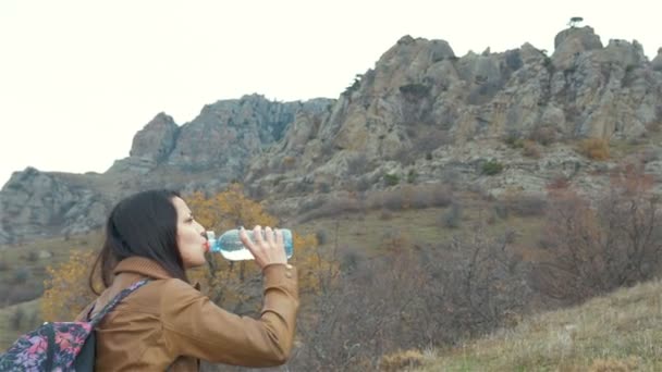 Kvinnan turist med ryggsäck dricksvatten i naturen — Stockvideo