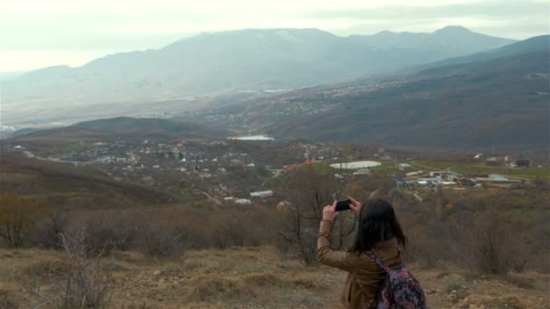 Ung kvinna selfie under solnedgången på berget med utsikt över landskapet — Stockvideo