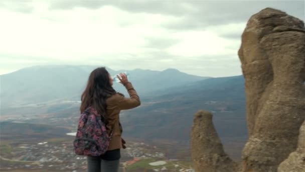 Kız içecekler dağlar arka planda bir şişe su — Stok video