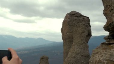 Genç bayan yürüyüşçü dağ zirvesinde akıllı telefonuyla fotoğraf çekiyor.