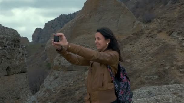 Uma jovem mulher assume o smartphone com a paisagem circundante da montanha — Vídeo de Stock