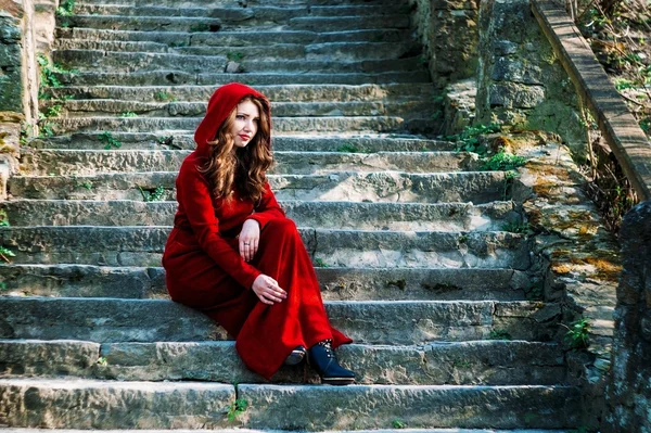 Όμορφη γυναίκα στο κόκκινο φόρεμα που κάθονται σε παλιά βήματα — Φωτογραφία Αρχείου
