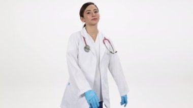 Kadın doktor kollarını kıvırıp gülümserken beyaz arka planda onlara doğru ilerliyor..