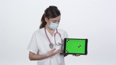 Doktor yeşil ekranlı tablet kullanırken maske takıyor..