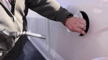Birisi benzin deposuna benzin koyuyor ve kapı kolunu kilitliyor..
