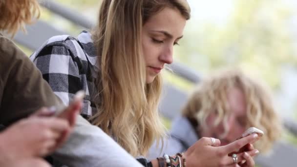 Panning Vista Amigos Adolescentes Saindo Olhando Para Telefones Inteligentes Sentados — Vídeo de Stock