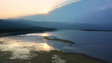 Düşük su seviyeleriyle gölün üzerinden geri geri uçup özel rıhtımlara giden teknelere bakıyoruz..