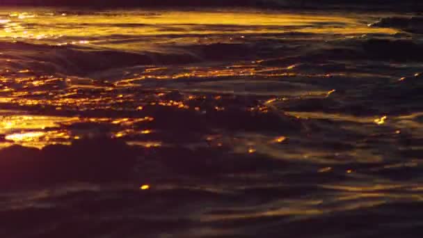 Vågor som täcker och avslöjar en klippa i solnedgången — Stockvideo