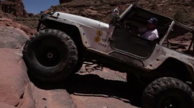 White Jeep Climbing Tiers of Rocks