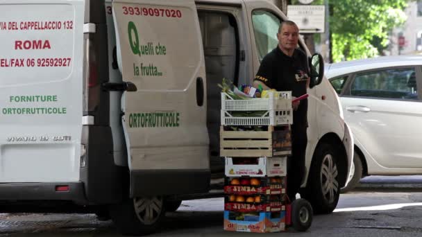 Człowiek dostawy stoi obok jego dostawczy i stos owoców w Rzymie, Włochy. — Wideo stockowe