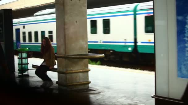 Dziewczyna siedzi na ławce w dworzec kolejowy — Wideo stockowe