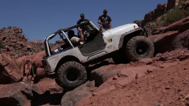 Männer beobachten, wie Jeep versucht, Felsen zu erklimmen — Stockvideo