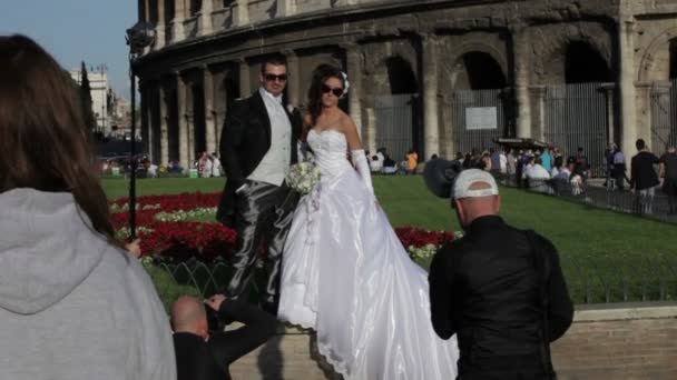 A newly married couple poses for pictures outside the Colosseum in Rome, Italy. — Stock Video