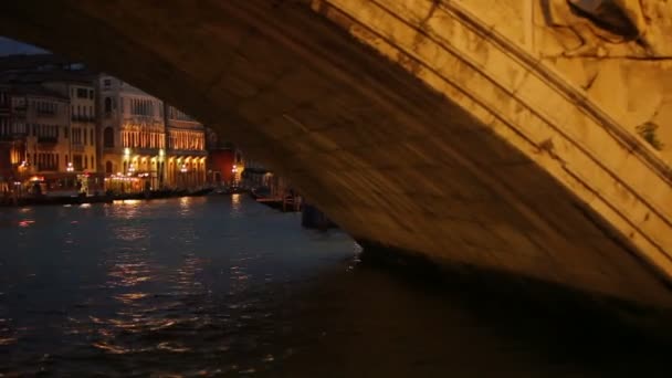 Flotando bajo un puente por la noche en Venecia — Vídeo de stock