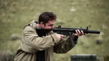 Tan ceketli adam bir Mp5 vuruyor