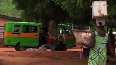 Tarafından Afrika'da bir köyde kafasındaki bir kutu ile yürüyen kadın.