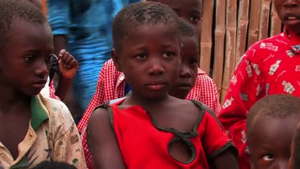 Jeune fille en Afrique regarde quelqu'un hors caméra entouré d'autres enfants . — Video