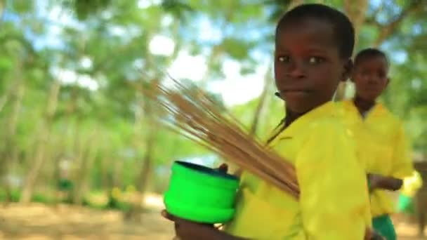 Glimlachend Keniaanse jongen uitvoering van stro en een emmer — Stockvideo