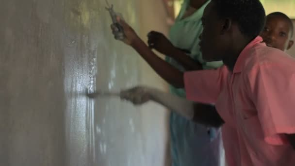 Niños pintando una pared en un pueblo de Kenia . — Vídeos de Stock