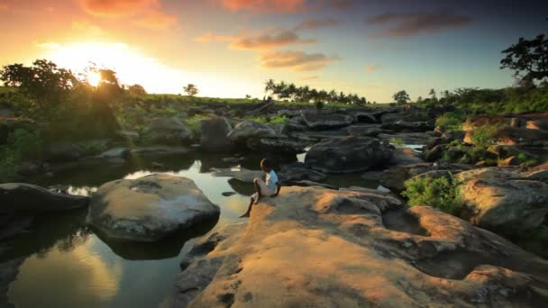 Kind sitzt bei Sonnenuntergang auf einem Felsen in Kenia. — Stockvideo