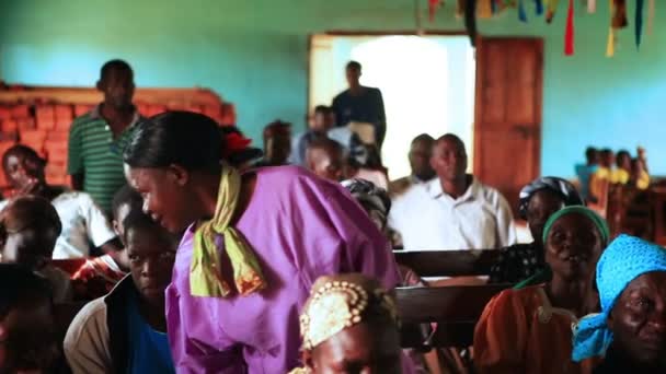 Een vrouw staat, spreekt; anderen zitten, luisteren tijdens aanbidding in Kenia, Afrika — Stockvideo