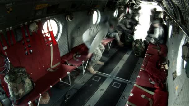 Un soldado entra por la escotilla trasera y se sienta en los bancos rojos. — Vídeos de Stock