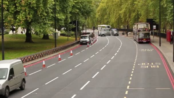 Auta jezdí kolem autobusové zastávky v Londýně. — Stock video