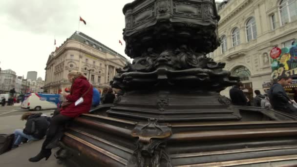 Nő ül az Eros szobor Piccadilly cirkusz, London — Stock videók