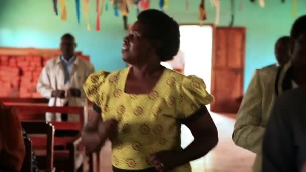 Mensen zingen en dansen tussen kerkbanken en in het gangpad tijdens aanbidding in Kenia, Afrika. — Stockvideo