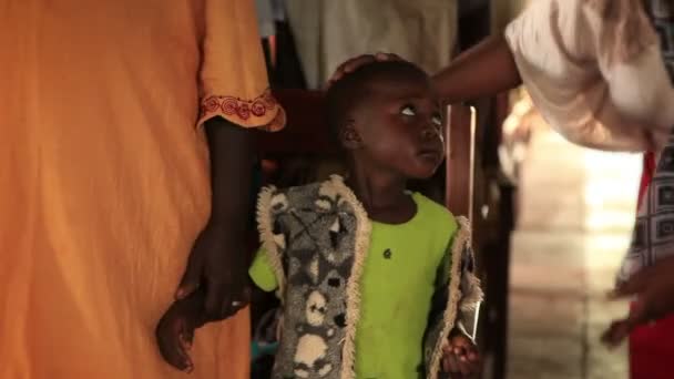 Una donna conforta un bambino nervoso mentre gli adulti ondeggiano intorno a loro in Kenya, Africa — Video Stock