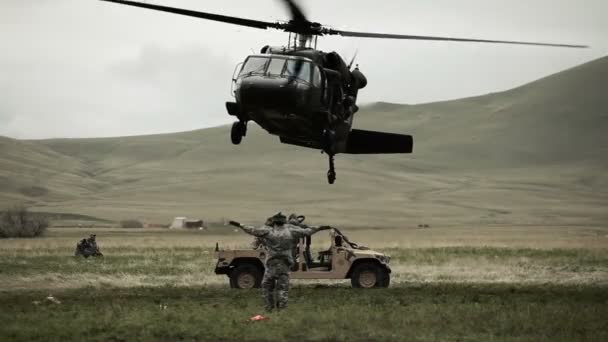 Hubschrauber schwebt über Humvee, während Soldat dem Piloten Signale gibt — Stockvideo